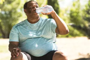 older overweight runner man is drinking water and sweating