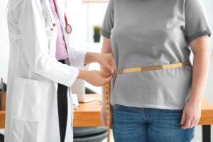 doctor measuring waist of overweight woman