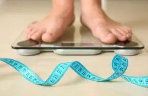 measuring tape in front of feet on weight scale