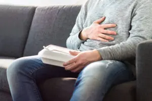 Man sitting on the couch with heartburn. 